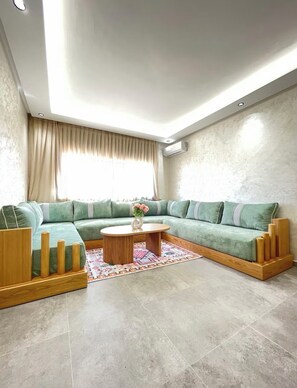 A modern living room with a sectional sofa, a wooden coffee table, and a patterned rug. - Spacious and elegant apartment in Gueliz, all on foot (Marrakech)