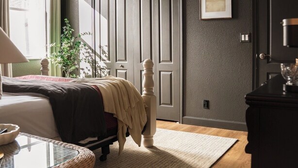 Une chambre à coucher comprenant un lit, une table de chevet, une commode et un ventilateur de plafond.