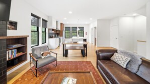 A modern living room with a fireplace, a sofa, a coffee table, and a dining area with a table and chairs.
