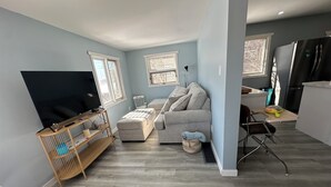 Un espacio habitable compacto con sofá, televisión, una mesita y una zona de cocina.