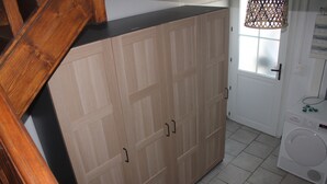 A laundry room with a washing machine, wooden cabinets, and a window with a patterned curtain. - Two-room apartment (Castelnau-Rivière-Basse)
