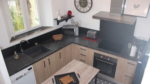 A modern kitchen with a dishwasher, microwave, toaster, and oven. - Two-room apartment (Castelnau-Rivière-Basse)