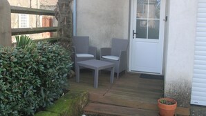 A patio area with wicker furniture, a white door, and a potted plant. - Two-room apartment (Castelnau-Rivière-Basse)