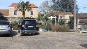 A paved driveway with two parked cars and a house in the background. - Two-room apartment (Castelnau-Rivière-Basse)