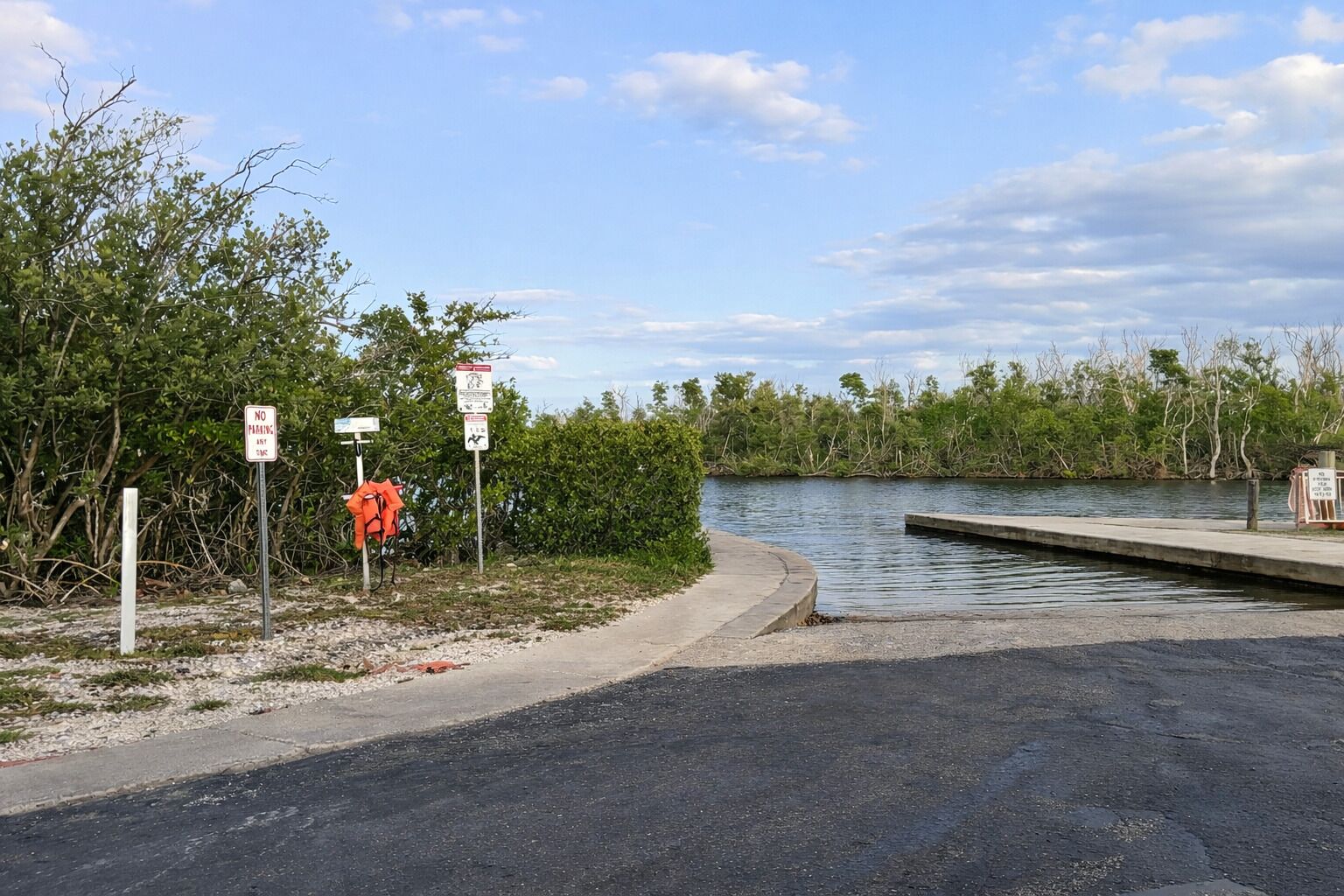 Une zone riveraine dotée d’un quai, de panneaux indiquant qu’il est interdit de se garer et bordée par une étendue d’eau.