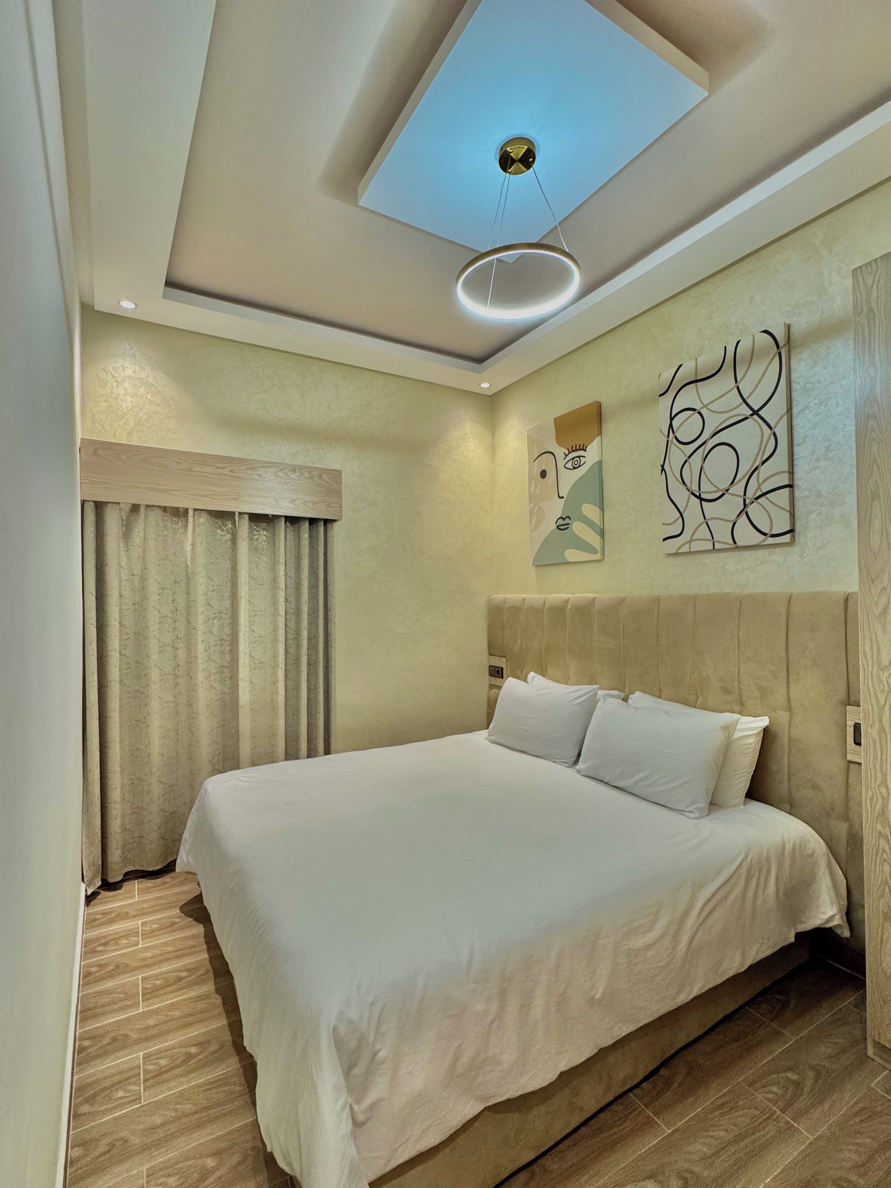 A bedroom with a bed, a ceiling light, and artwork on the wall.