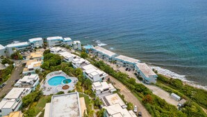 Oversigtsbillede af et kysthotel med flere bygninger, en swimmingpool og en strand.
