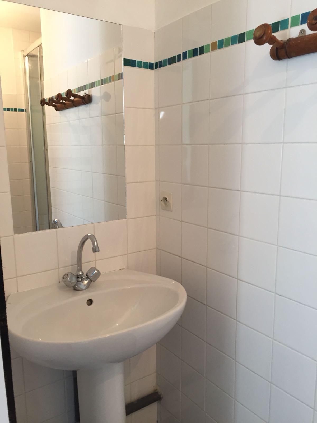 Een badkamer met een wit wastafel, een spiegel en een douchehoek.