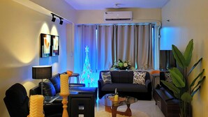 A modern living room with a chandelier, a sofa, a coffee table, and a Christmas tree. - Spectacular 2.5BR Connected to Eastwood  Mall (Quezon City)