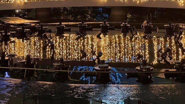 A building with a tree decorated with blue lights, a water feature, and string lights. - Spectacular 2.5BR Connected to Eastwood  Mall (Quezon City)