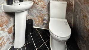 A bathroom with a marble wall, a white sink, a toilet, and a mirror. - Lahza Tiny House (Çamlıhemşin)
