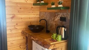 A compact wooden cabin with a kitchenette, including a sink, stove, and green mugs. - Lahza Tiny House (Çamlıhemşin)