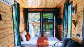 A cozy cabin with a bed, a sofa, a small table, and a colorful rug. - Lahza Tiny House (Çamlıhemşin)