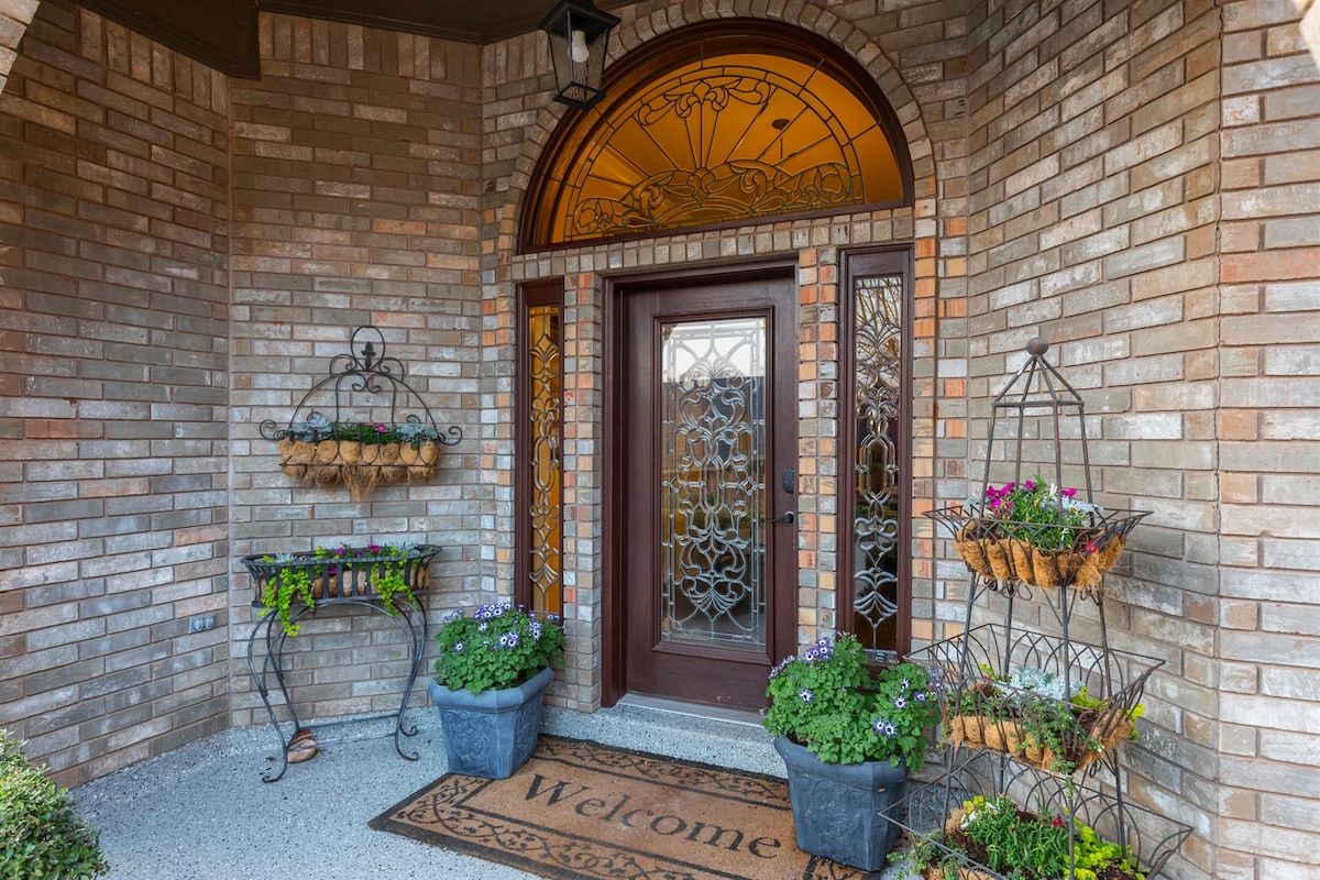 A brick entrance with a welcome mat, potted plants, and decorative metal baskets.