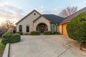 Une maison de plain-pied en briques, avec une entrée à l’avant, un garage et une pelouse bien entretenue.