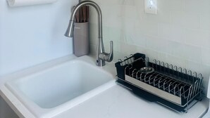 A kitchen with a sink, a dish rack, and a roll of paper towels. - Hidden Gem in the Heart of Capitol Hill (Denver)