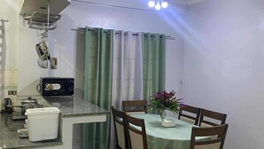 Ein Essbereich mit Tisch, Stühlen, Deckenventilator und einer Küchenzeile mit Mikrowelle.