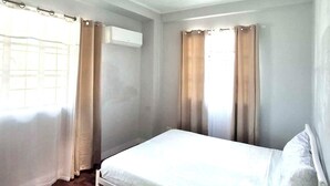 Ein Schlafzimmer mit einem Bett, Holzboden und Vorhängen.