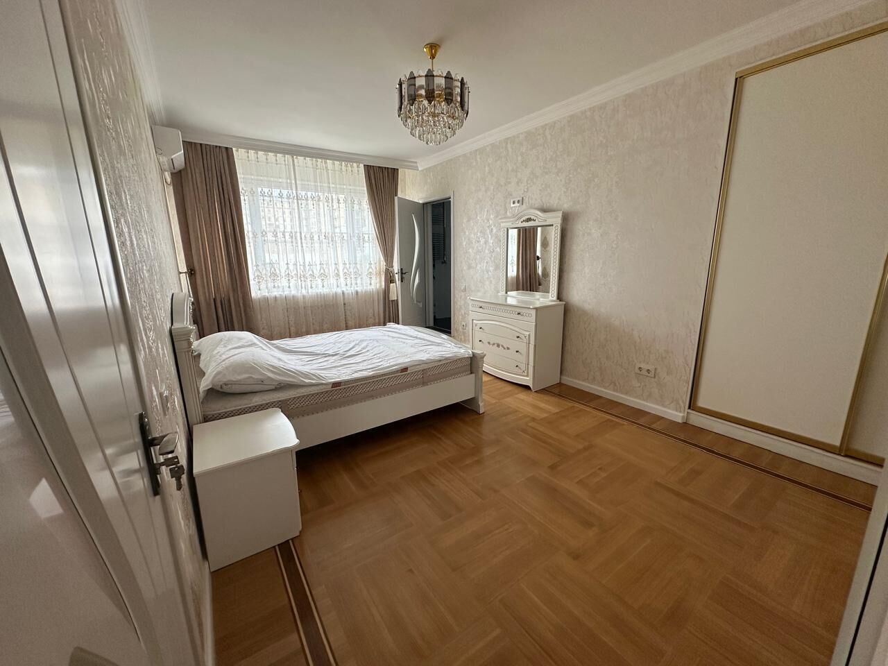 Un dormitorio con cama, cómoda, espejo y candelabro.