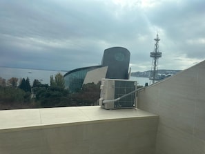A modern building with a curved facade and a clock tower, overlooking a body of water. - Formula 1 View apartment in center of Baku (Baku)