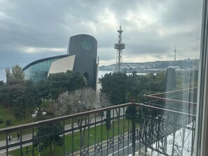 A modern building with a curved facade and a prominent clock tower, surrounded by greenery and a clear sky. - Formula 1 View apartment in center of Baku (Baku)