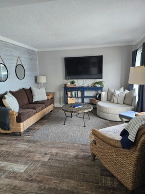 A living room with a brown sofa, a round coffee table, a blue sideboard, and a flat-screen TV. - A308 at the Myrtle Beach Resort
Beautiful Oceanfront 2 bdrm condo. (Myrtle Beach)