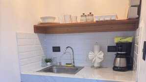 A compact kitchen with a sink, a coffee maker, a trash bin, and a refrigerator. - Walk Everywhere , Budget Stay w/ AC + WiFi #1 (La Fortuna)