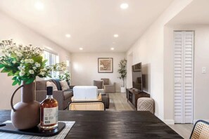 Ein modernes Wohnzimmer mit Sofa, Sesseln, Couchtisch und Fernseher.