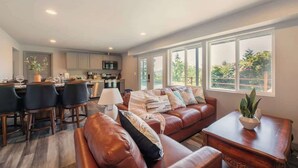 A spacious living area with a leather sofa, a dining table, and a kitchen in the background. - Bright 2BR Lower Unit | Relaxing Yard & Great Spot (Bellevue)