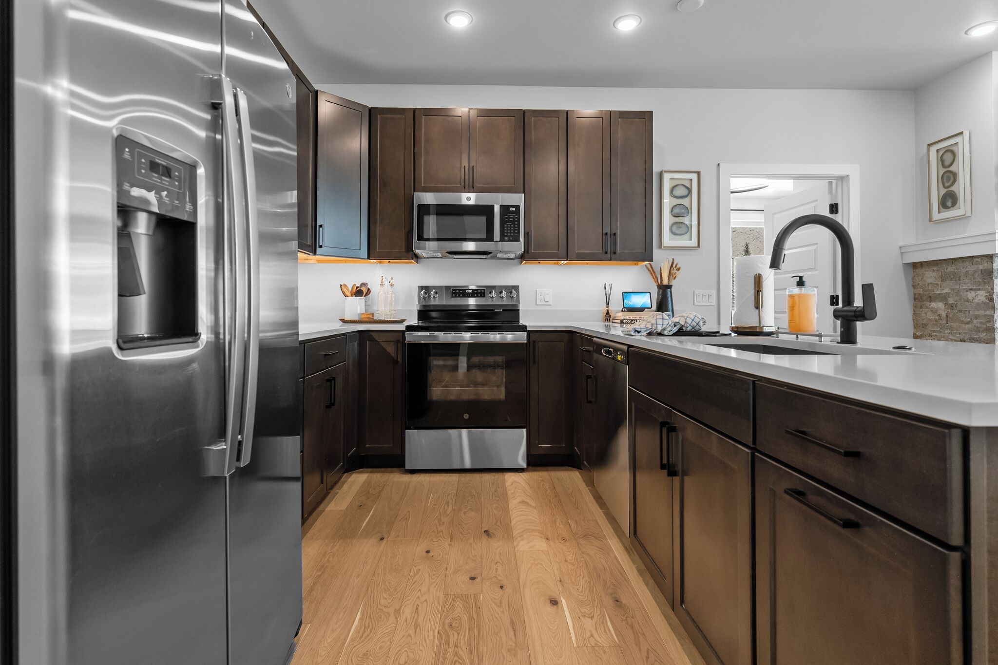 A modern kitchen with stainless steel appliances, dark wood cabinets, and a white countertop.