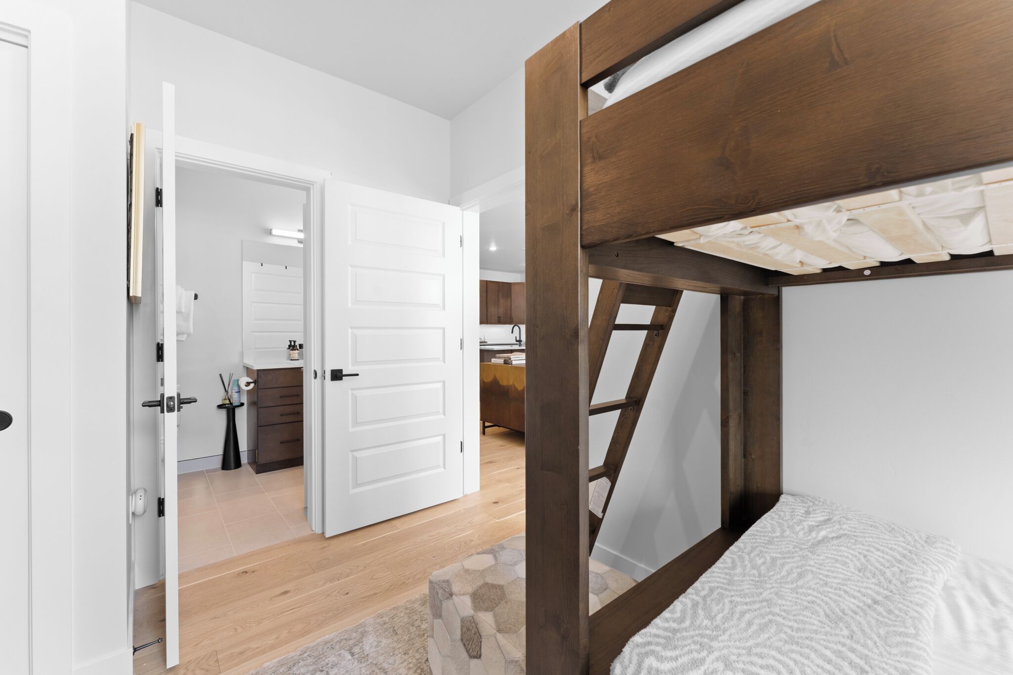 A room with a bunk bed, a white door leading to another room, and a staircase.