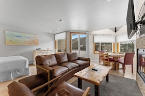 A modern living room with a brown leather sofa, a wooden coffee table, and a dining area with wooden chairs and a table. - Ls1496-0 (Keystone)