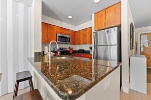 A modern kitchen with granite countertops, stainless steel appliances, wooden cabinets, and a built-in microwave. - Ls1496-0 (Keystone)