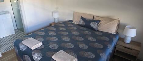 Hotelkamer met een groot bed, twee nachtkastjes en een zichtbare badkamer op de achtergrond.