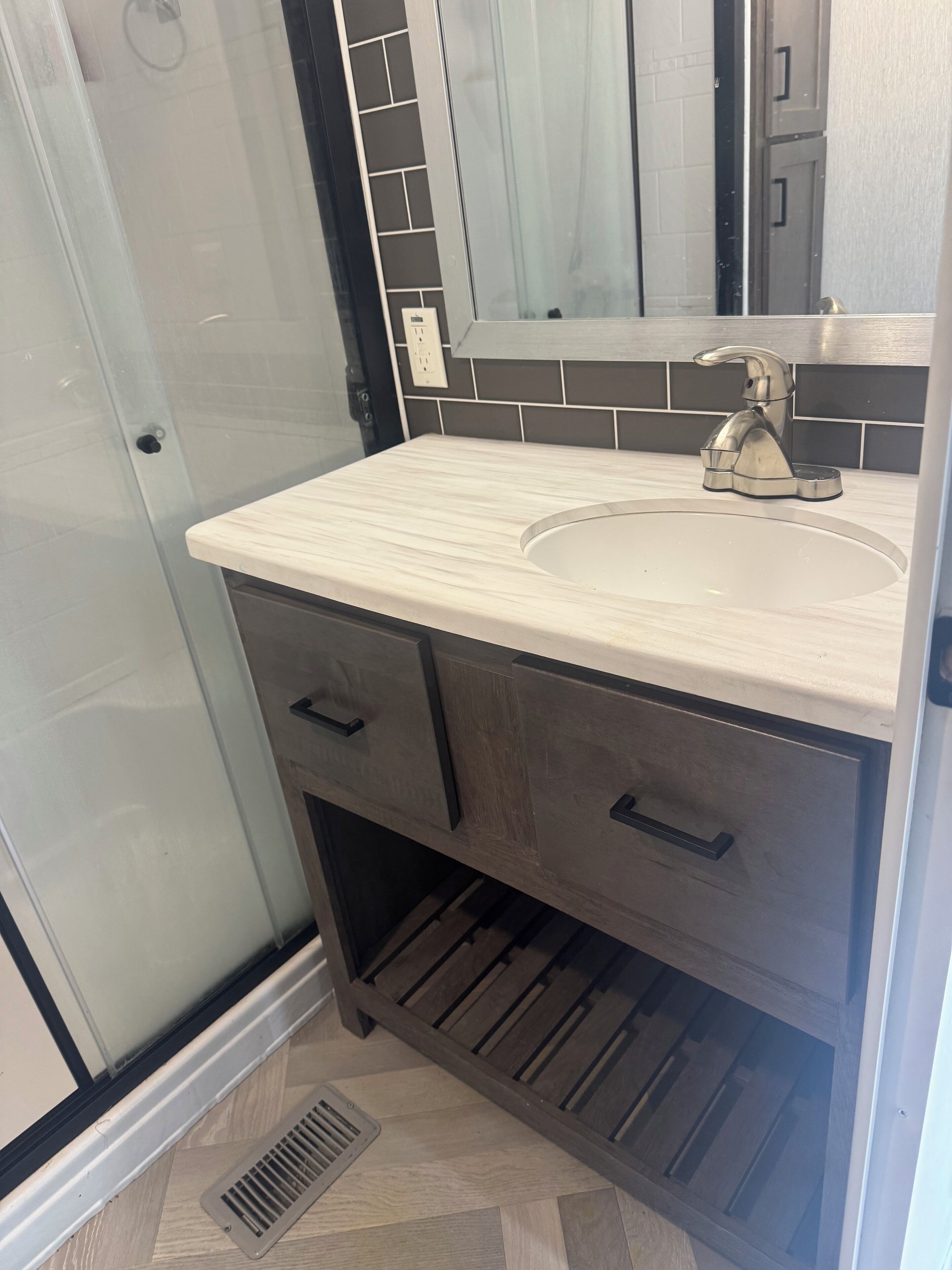 Un baño con cabina de ducha de vidrio, un lavabo con grifo moderno y un mueble con cajones.