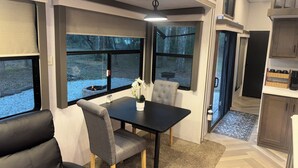 Un intérieur de camping-car moderne comprenant un coin repas, des sièges et une cuisine.