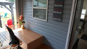Quarto com escrivaninha de madeira, uma cadeira, janela e um aviso fixado na parede com as regras da casa.