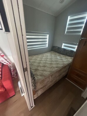 A small, narrow room with a single bed, a window with blinds, and a door. - Hangout at newly renovated large corner lot Sherkston Shores Resort at lake Erie (Port Colborne)