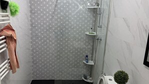 Een moderne badkamer met douche, toilet en wastafel.