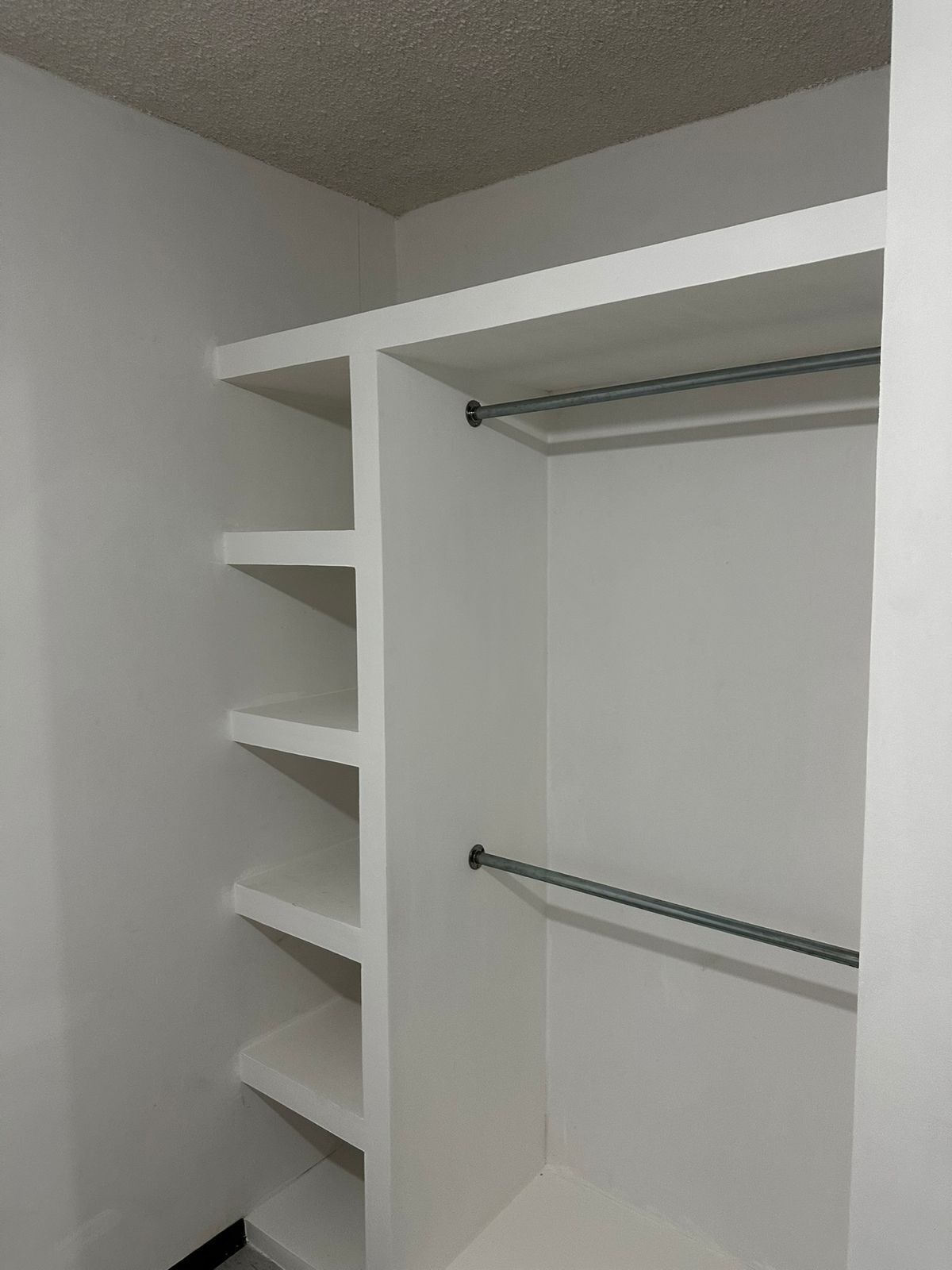 A white closet with multiple shelves and two metal rods.