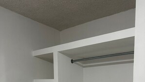 Un placard blanc avec plusieurs étagères et deux barres métalliques.