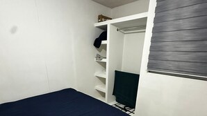 Une chambre à coucher avec un lit, une armoire et une fenêtre équipée de stores.