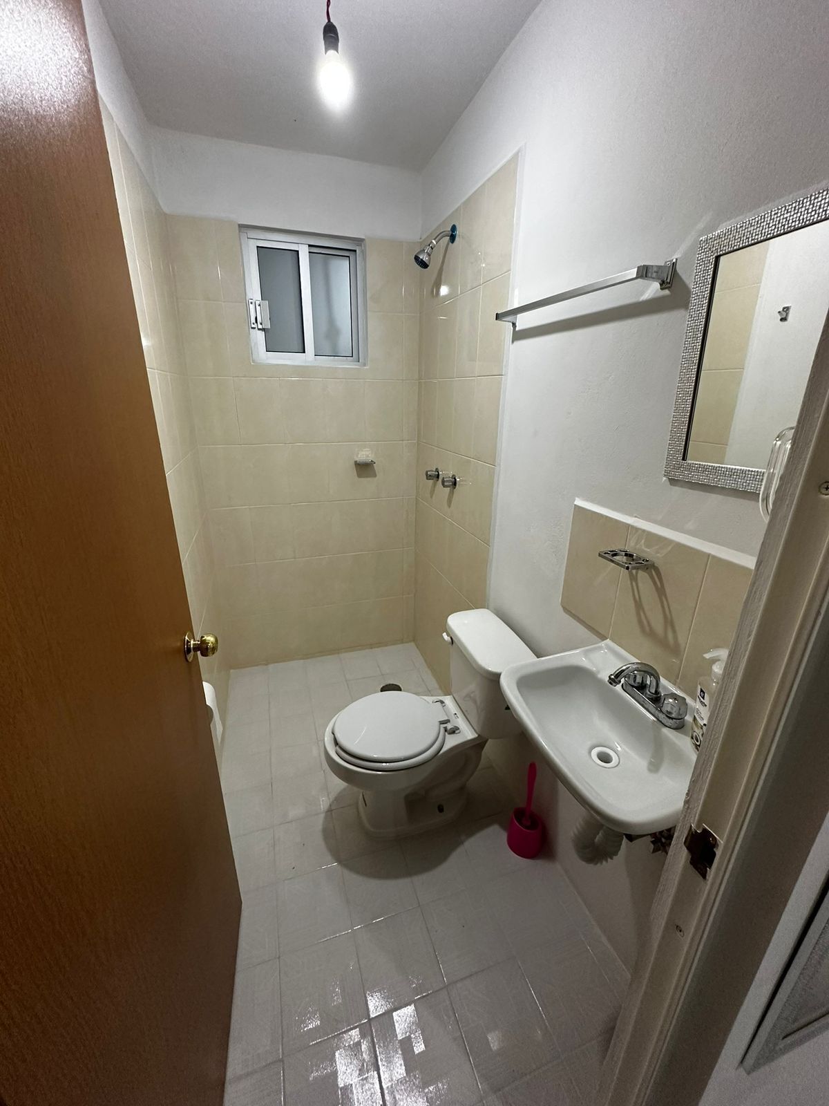 A bathroom with a toilet, sink, mirror, and shower.