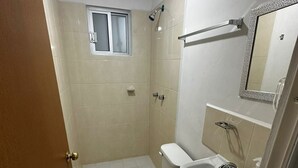Une salle de bain équipée de toilettes, d’un lavabo, d’un miroir et d’une douche.