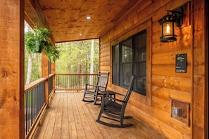 A wooden porch with rocking chairs, a lantern, and a sign indicating the address. - Willowcrest: Brand NEW, Lake Access, Dog Friendly, Hot Tub (Oakland)