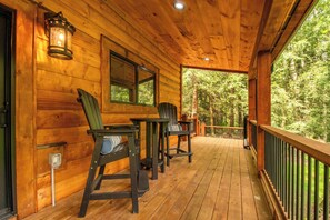 A wooden deck with two chairs and a table, overlooking a forested area. - Willowcrest: Brand NEW, Lake Access, Dog Friendly, Hot Tub (Oakland)