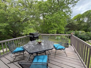 Een terras met een tafel en stoelen, omringd door bomen.