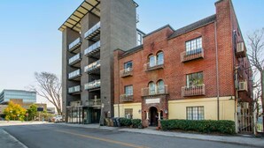 A multi-story building with a mix of brick and glass facades, balconies, and a visible entrance. - Prime football location- condo walking distance from stadium (Knoxville)