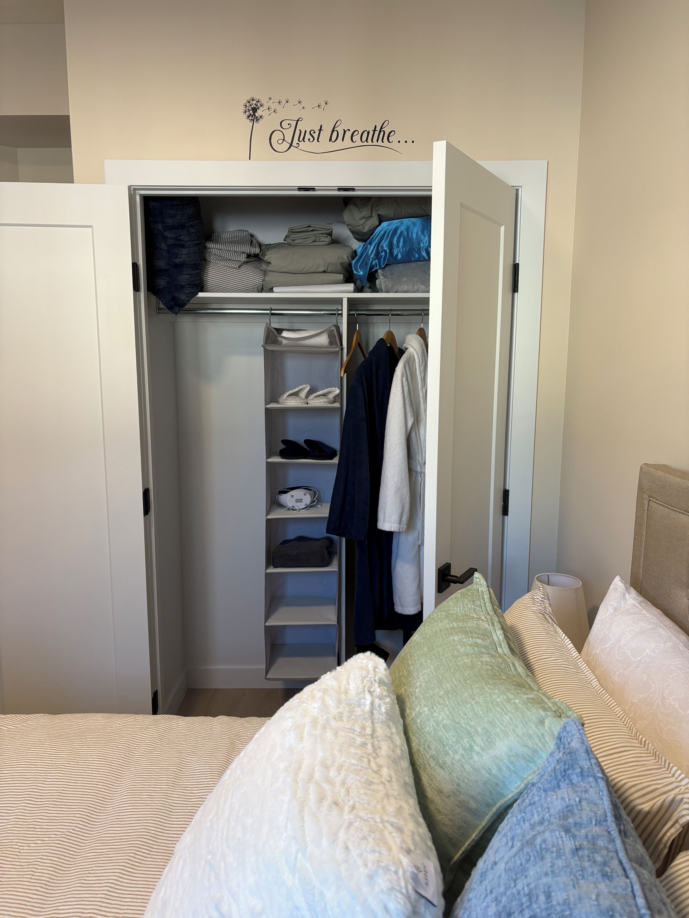 Ein Schlafzimmer mit Bett, Kissen, Nachttisch, Kleiderschrank und Wandbild.