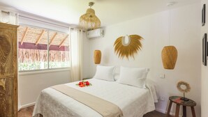 Um quarto com cama, janela com vista, piso de madeira e ar-condicionado fixado na parede.